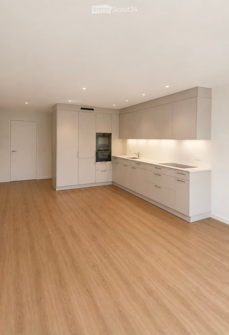 Modern kitchen with light-colored cabinets, wooden flooring, and built-in appliances including an oven, sink, and stove.