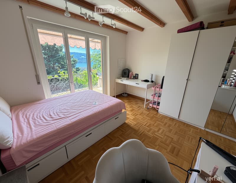 Bedroom. Bright bedroom with wooden flooring, large window offering a scenic view, bed with pink bedding, desk with laptop and accessories, wardrobe, and a mirror.