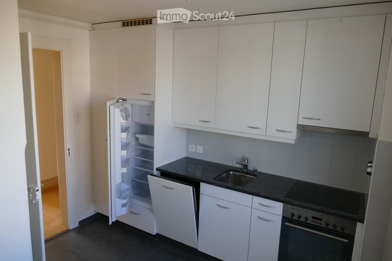 Modern kitchen with white cabinets, black countertops, stainless steel sink, and appliances including a refrigerator, stove, and oven.