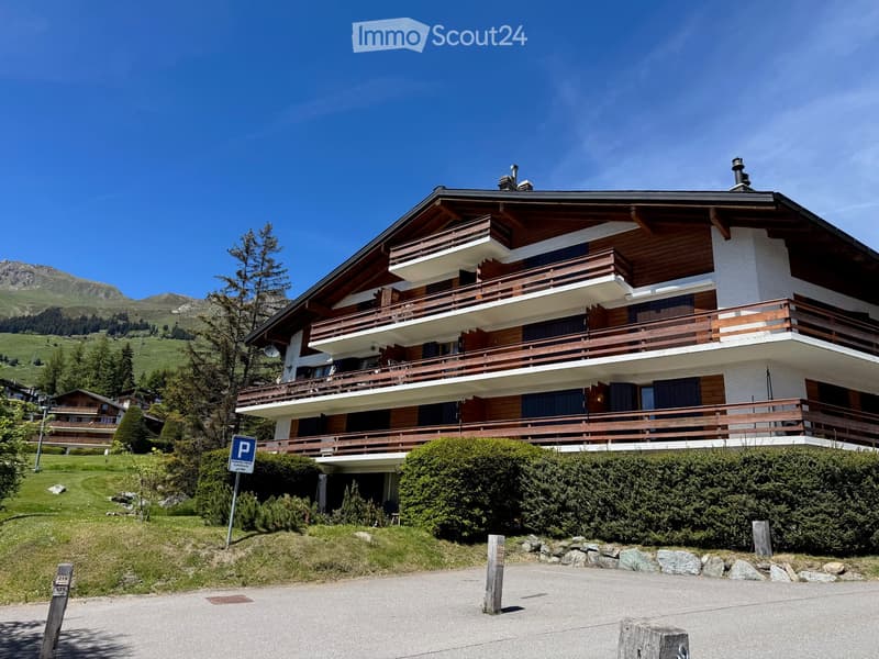 3 story house, wooden balcony, white wall, green grass, trees, parking sign