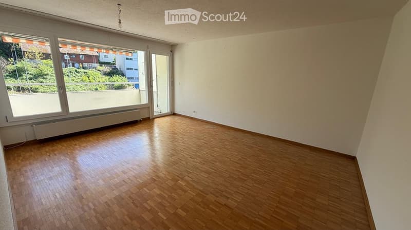 Empty room with wooden flooring, large windows, and a door leading to a balcony.