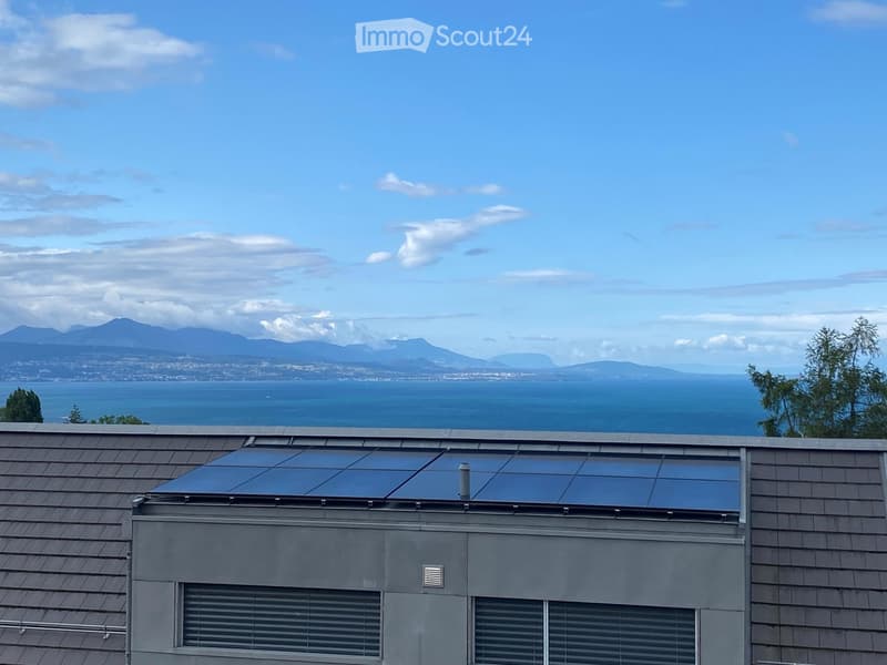 Roof with solar panels, overlooking a scenic ocean view with distant mountains and cityscape.