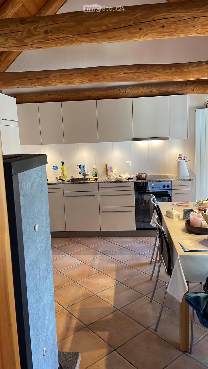 Modern kitchen with white cabinets, stainless steel appliances, tiled floor, and a wooden island with seating.