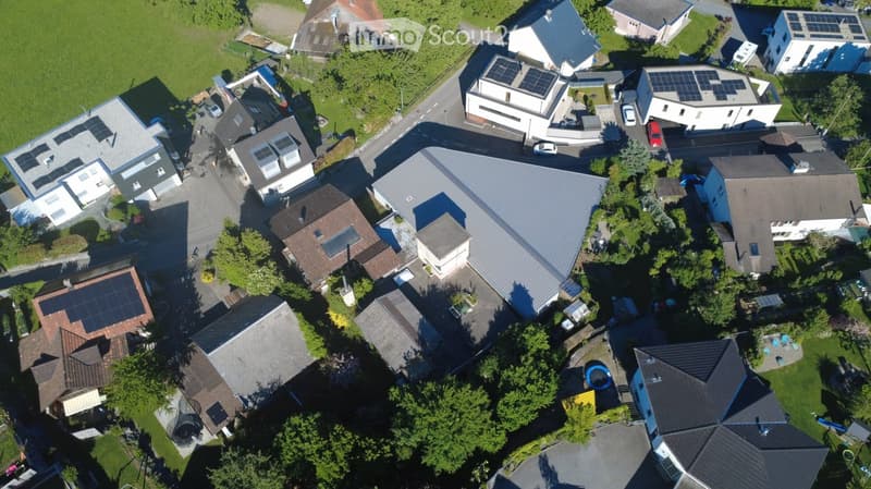 Aerial view of a residential neighborhood with multiple houses, solar panels on roofs, and a swimming pool visible in one yard.
