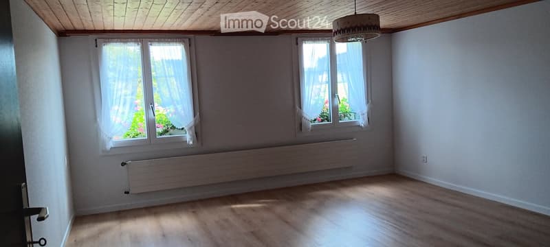 large room, white walls, wooden floor, two large windows, two radiators, wooden ceiling