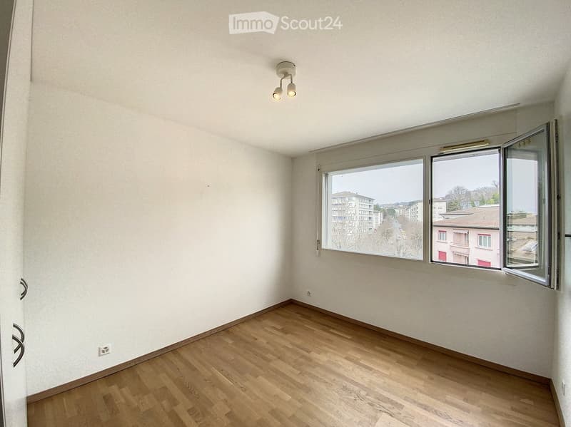 Unfurnished Room. Empty room with wooden flooring, white walls, and large windows offering a view of the cityscape.