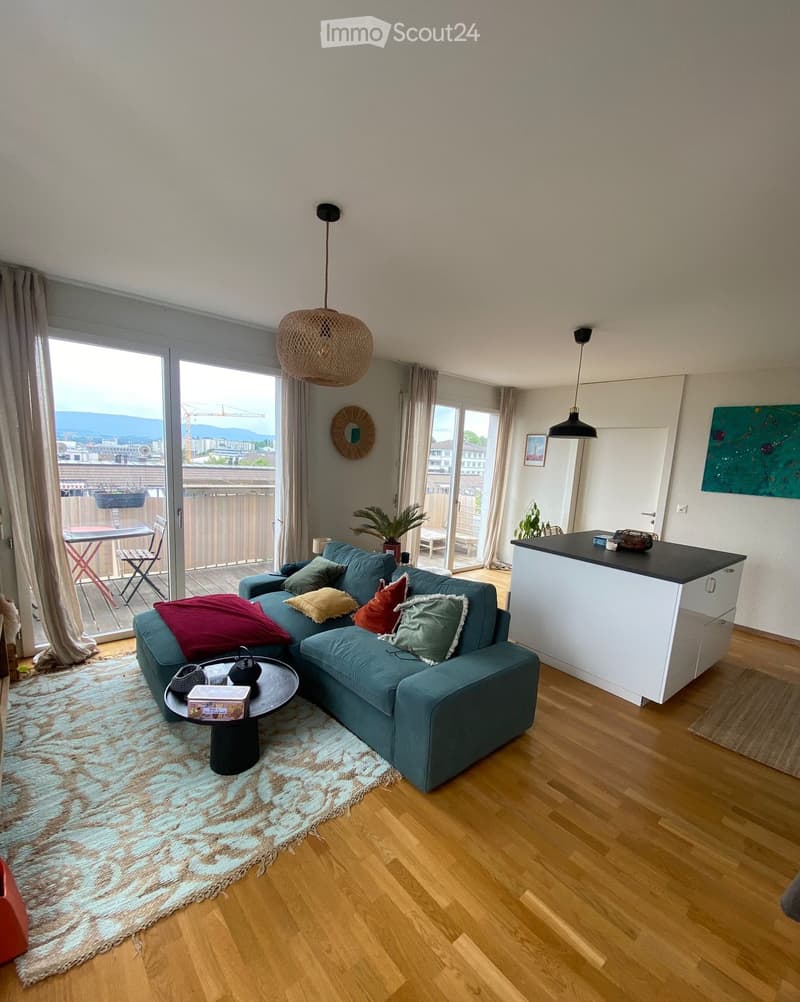 Living Room. Modern living room with a blue sectional sofa, coffee table, kitchen island, pendant lights, and a view of the city.