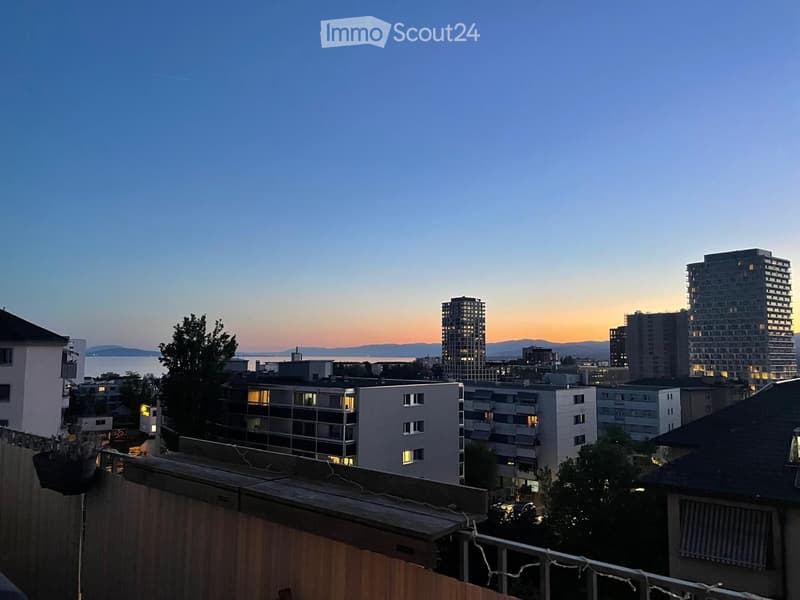 Balcony / Terrace. Balcony overlooking a cityscape at sunset, with multiple residential buildings, trees, and a distant body of water.
