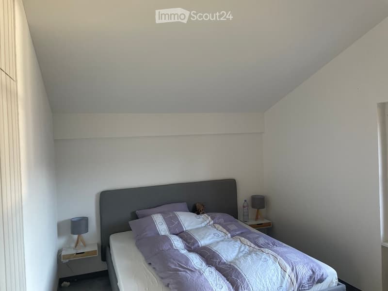 Bedroom with a grey headboard, white bed frame, purple bedding, two nightstands with lamps, and a small bottle on one nightstand.
