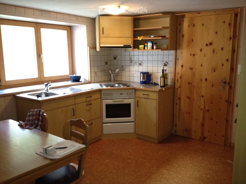 A cozy kitchen with wooden cabinets, a sink, an oven, a table with chairs, and various kitchen items on the counter.