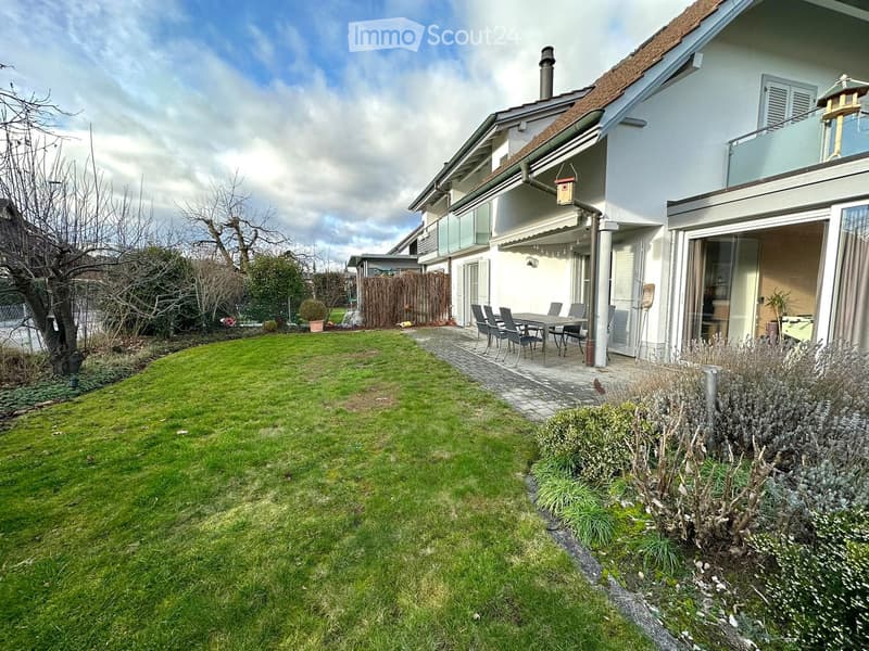Well-maintained garden with a lawn, patio area, and outdoor dining set.