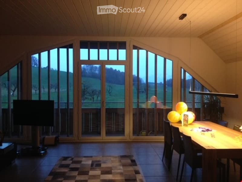 Furnished Room. Bright living space with large windows offering a scenic view, featuring a dining table, chairs, and decorative balls.