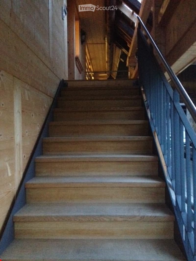 Corridor / Hallway. Wooden staircase with metal railing, wooden walls, and warm lighting.