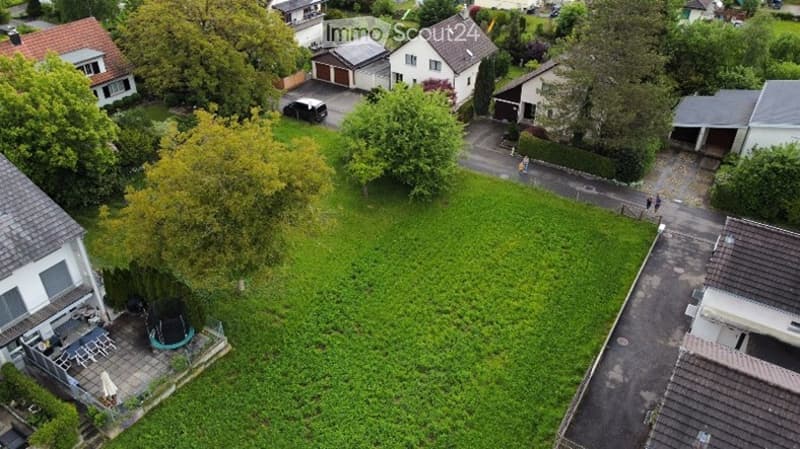 Aerial view of a residential neighborhood with multiple houses, green lawns, driveways, and trees.