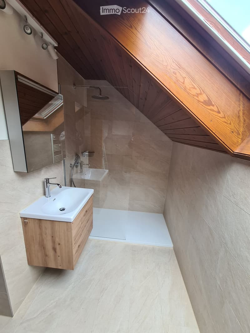 Bathroom with wooden ceiling, white sink, wooden cabinet, glass shower enclosure, mirror, and ceiling lights