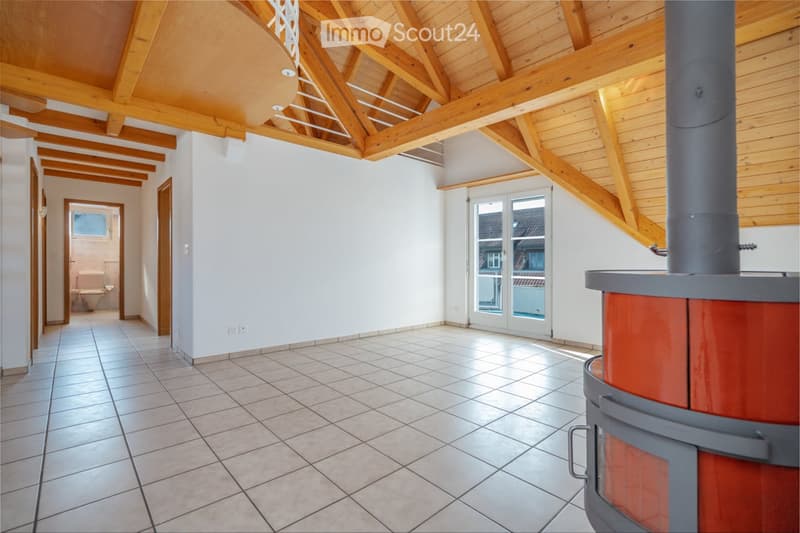 Bright hallway with wooden beams, tiled floor, and a visible fireplace. A bathroom is visible in the background.