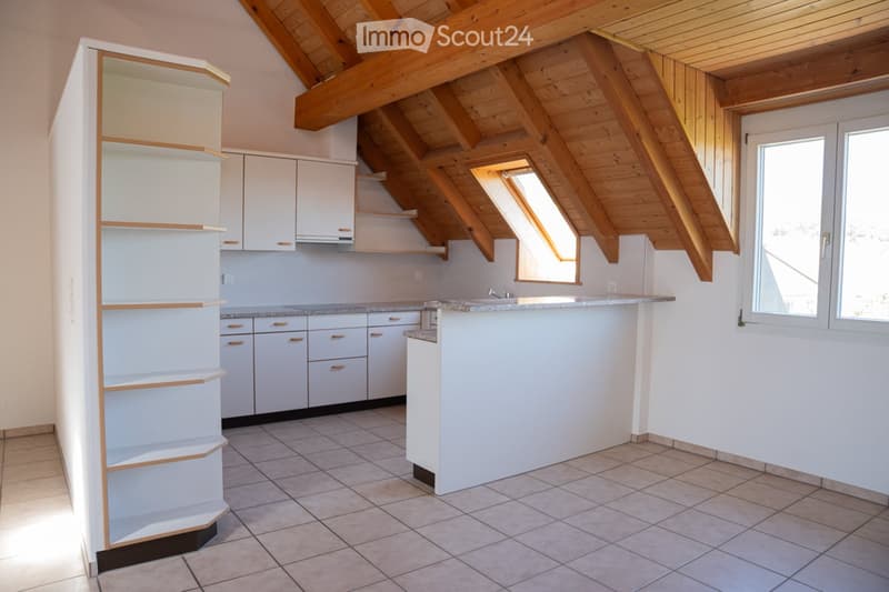 Bright kitchen with white cabinets, a central island, and a tiled floor. The ceiling features exposed wooden beams and skylights.