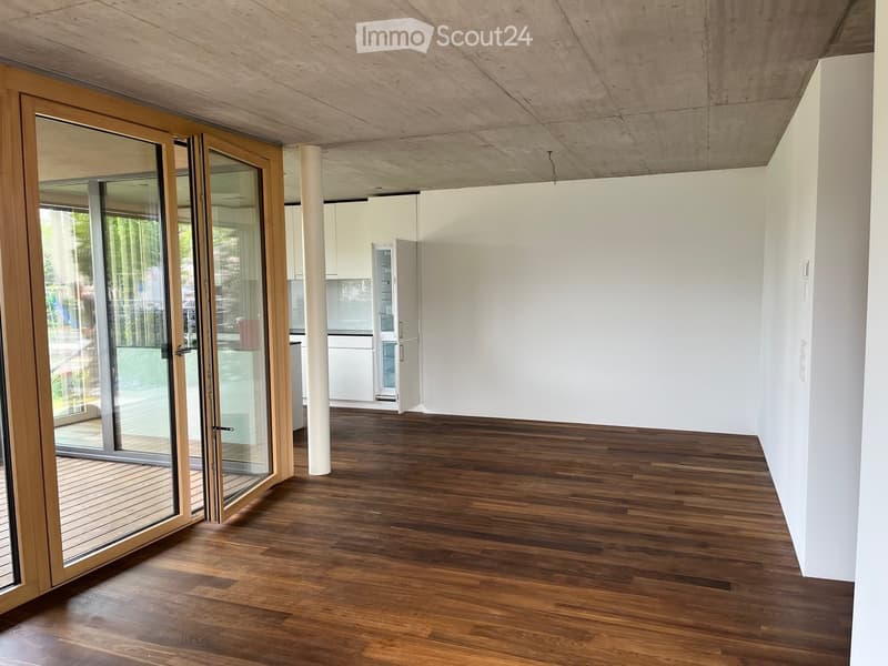 Empty room with wooden flooring, white walls, and large sliding glass doors leading to an outdoor deck.