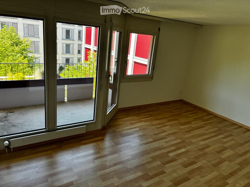 Empty room with wooden flooring, large windows, and a balcony with a metal railing.