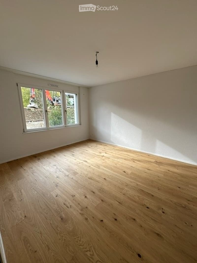 Empty room with wooden flooring and large windows, no furniture or equipment.