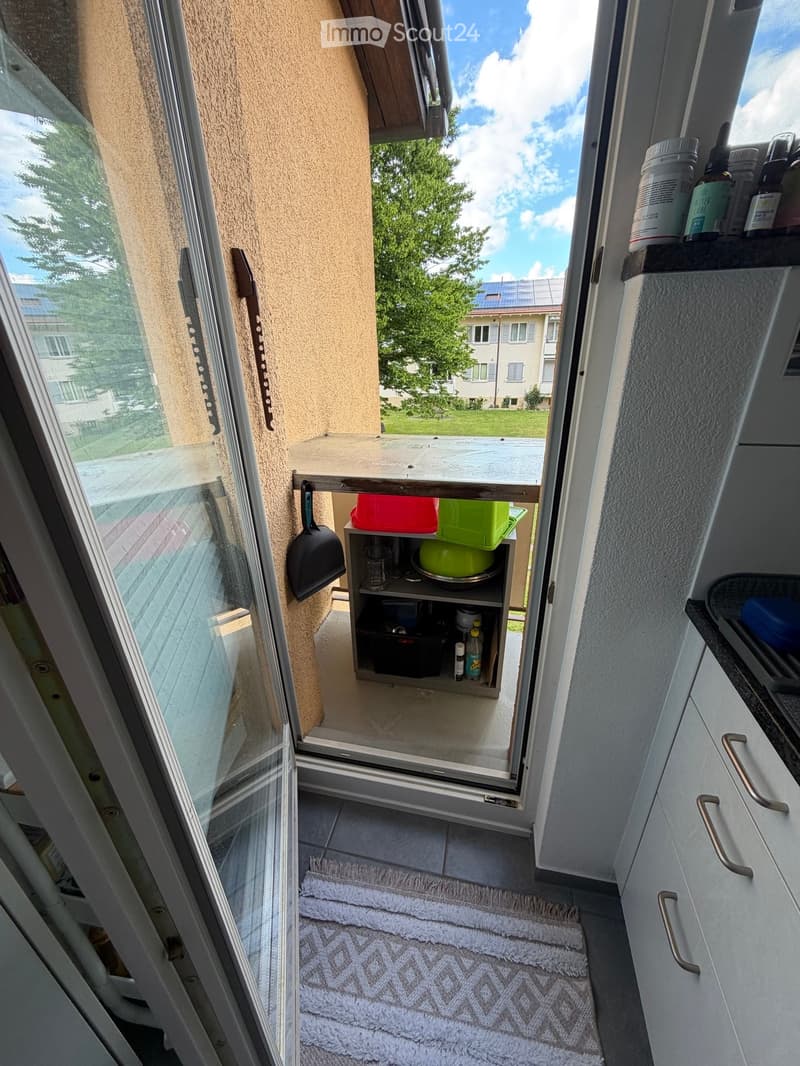Balcony with a small table, shelf, and view of the neighborhood.
