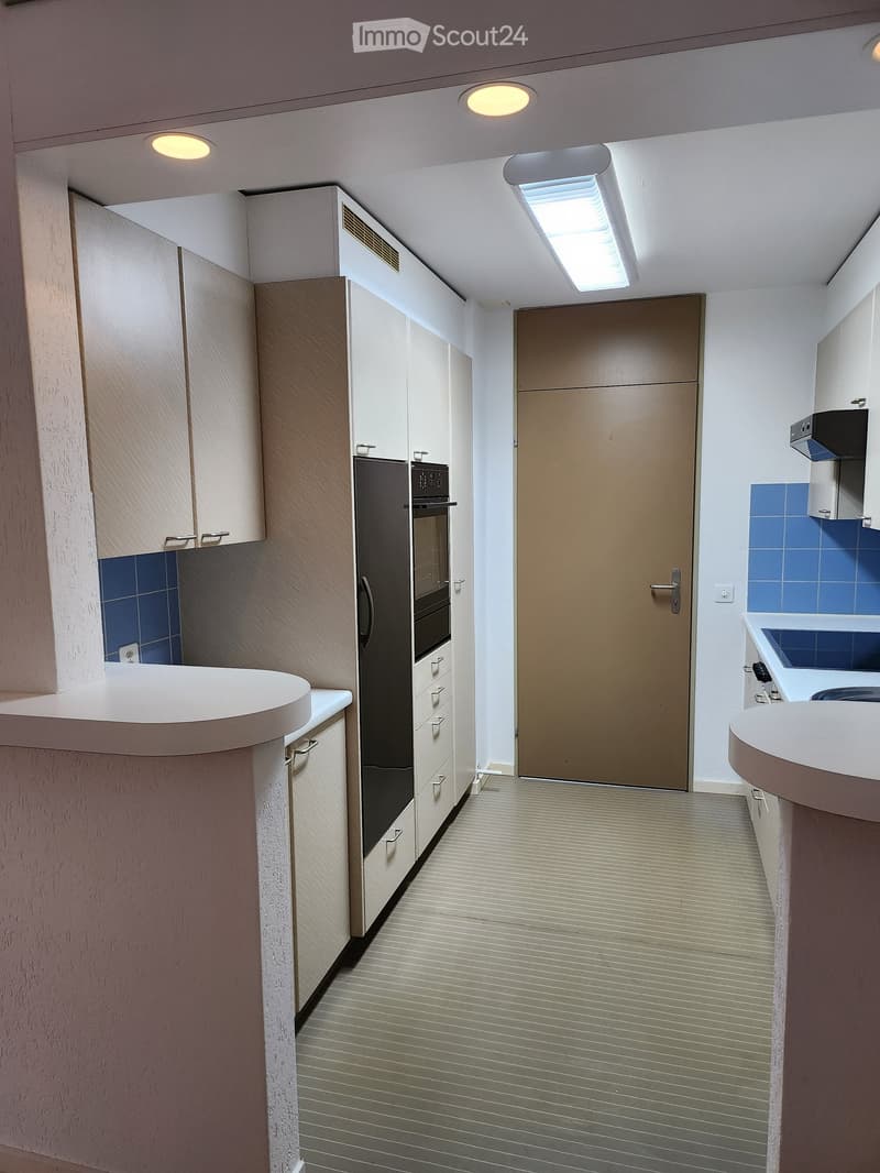 Modern kitchen with white cabinets, stainless steel appliances, and a sleek design. Features include a refrigerator, oven, sink, and built-in cabinets.