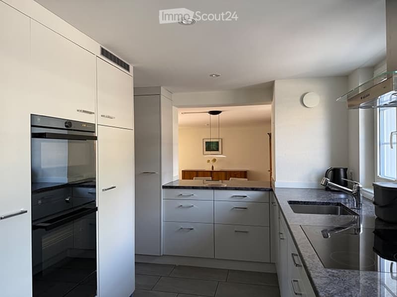 Modern kitchen with white cabinets, stainless steel oven, granite countertop, and double sink.