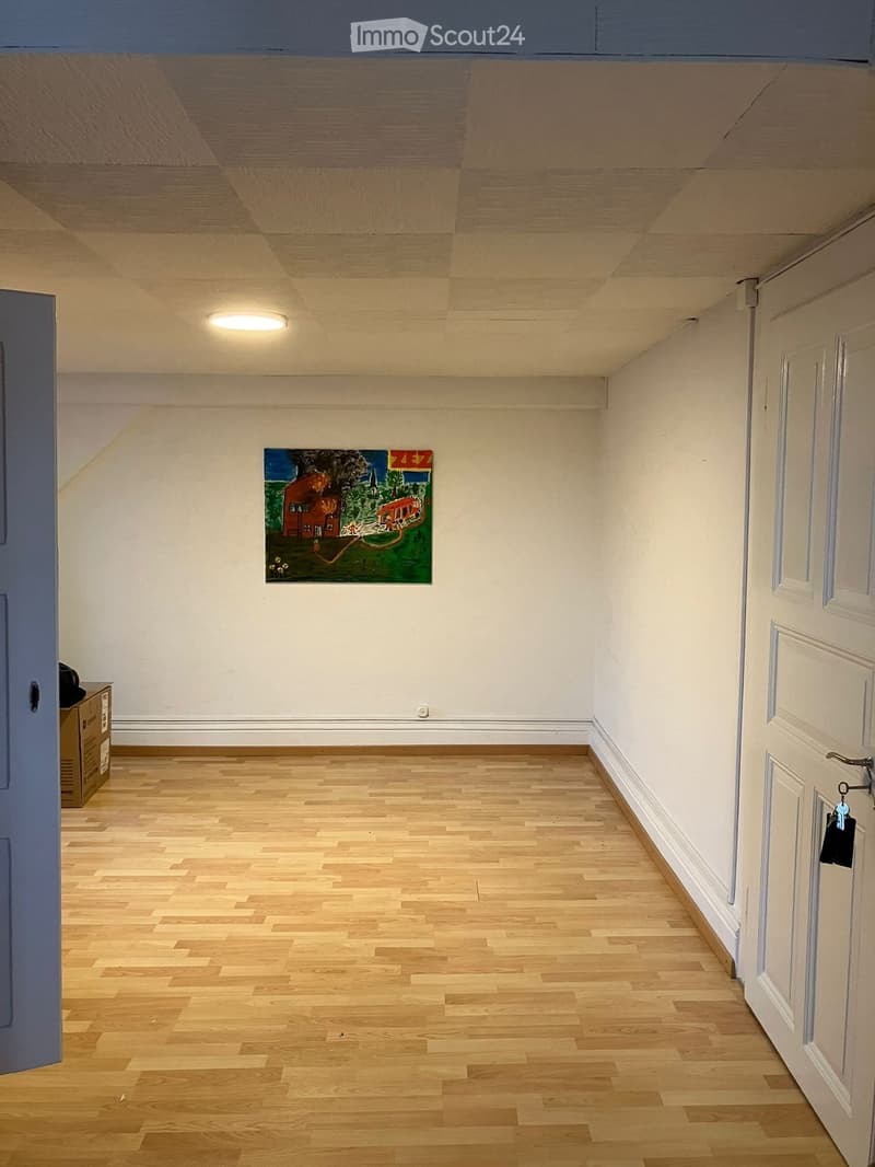empty room, wooden floor, white walls, painting on wall, open door, small cabinet