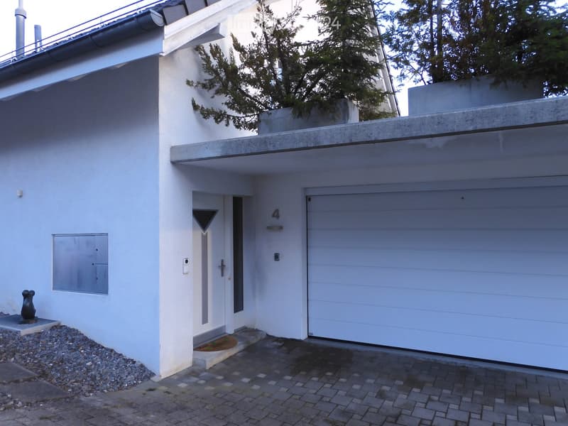 Modern two-story house with white exterior, garage, and small garden area.