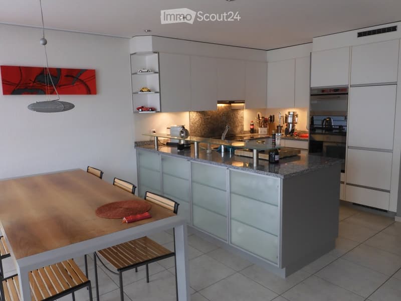 Modern kitchen with white cabinets, granite countertop, island, dining table with chairs, and various appliances.