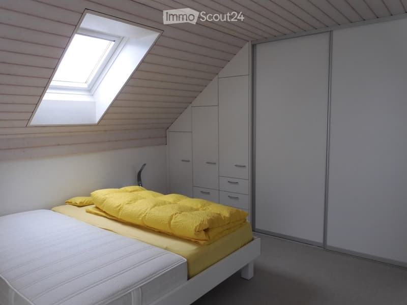 Bright bedroom with a white bed, yellow bedding, and built-in wardrobe. Skylight window provides natural light.