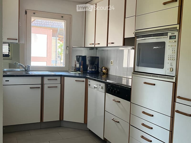 Modern kitchen with white cabinets, stainless steel appliances, and a black countertop.