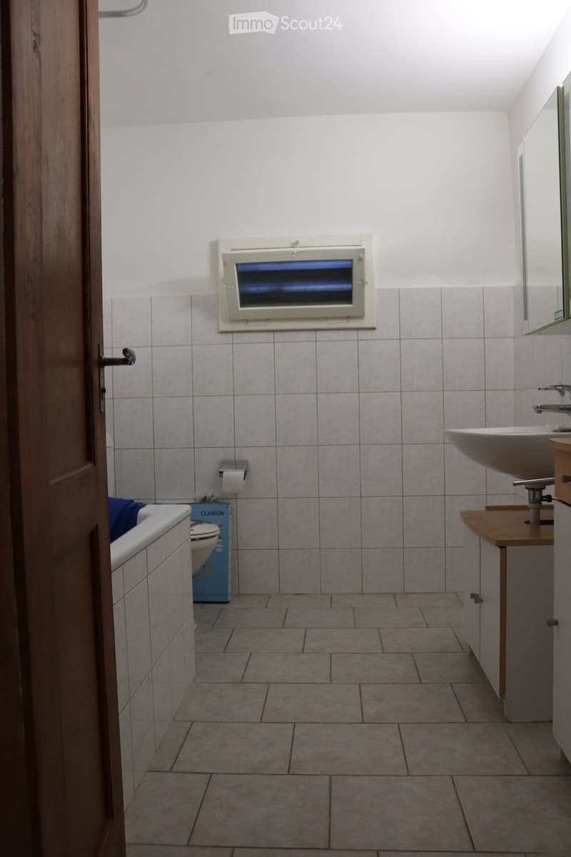 white tiles, bathtub, toilet, sink, mirror, cabinet, tissue roll