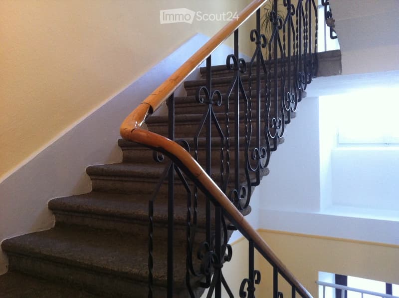 interior stairs, wooden handrail, wrought iron railings, carpeted steps, beige walls
