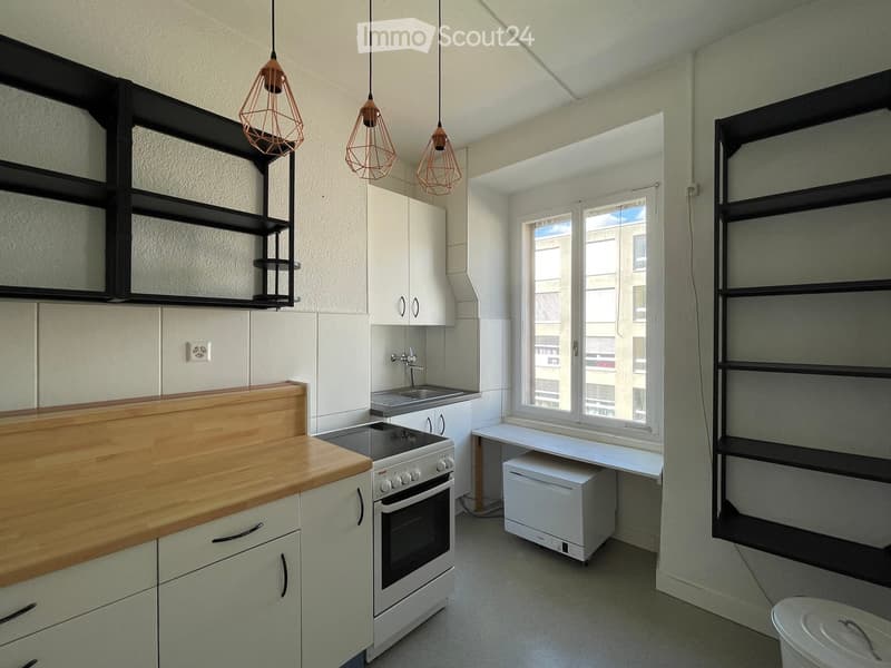 A modern kitchen with tiled floors, white cabinetry, wooden countertops, modern appliances, and hanging lamps.