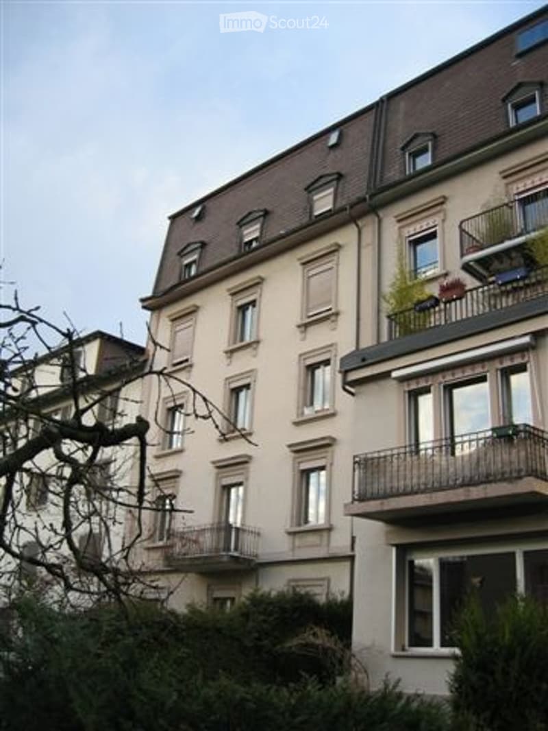 3 story building, beige walls, brown roof, multiple windows, balconies