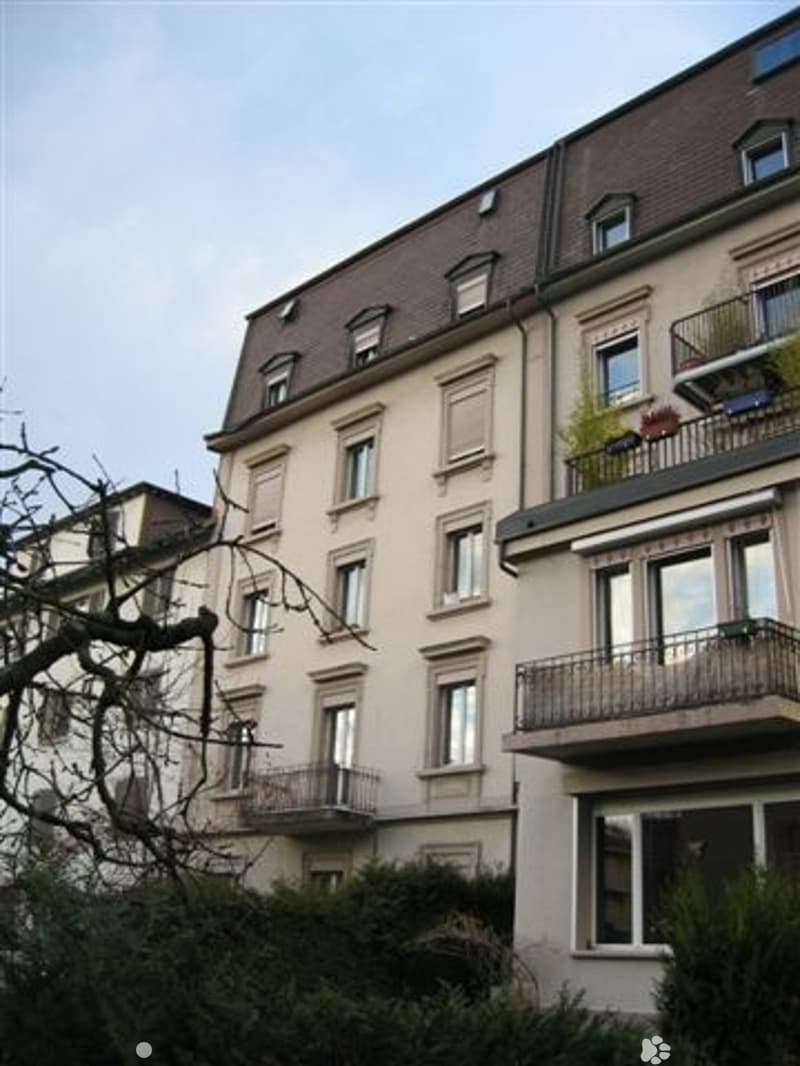 3 story building, beige walls, brown roof, multiple windows, balconies