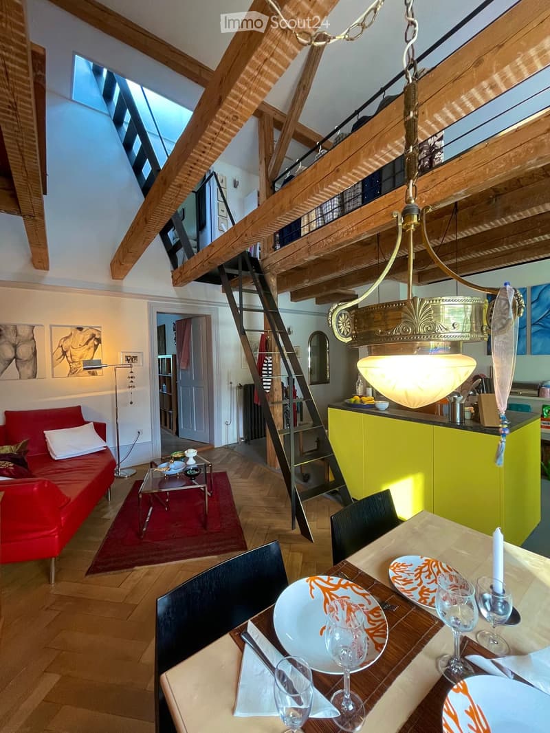 dining room with wooden beams, red couch, glass table, yellow kitchen, ladder, chandelier, red carpet