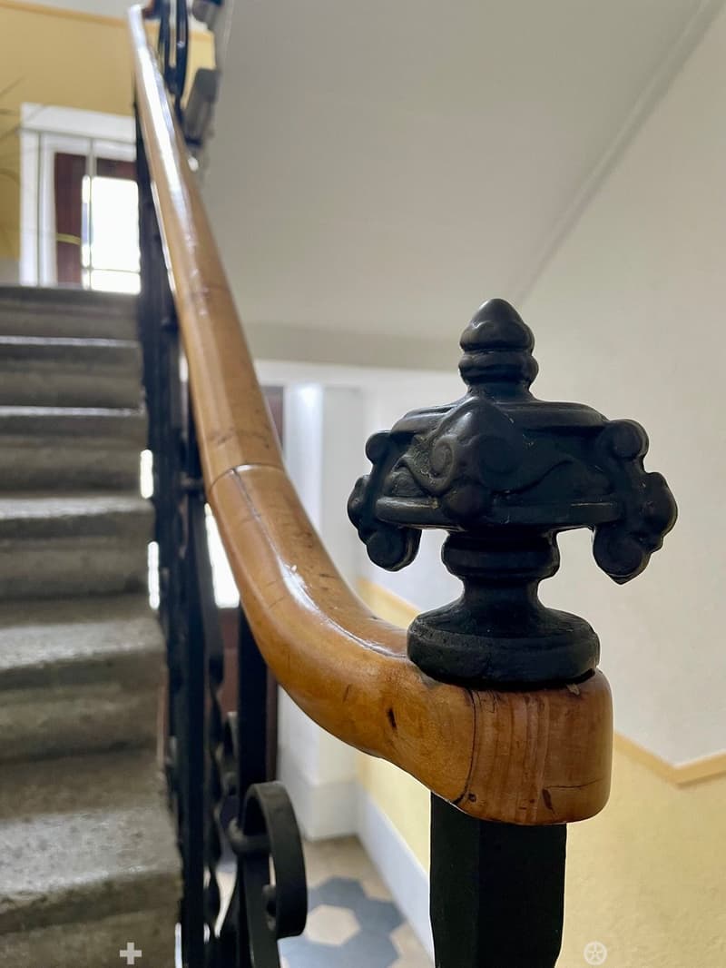 wooden handrail, black metal railing, wooden steps, white walls