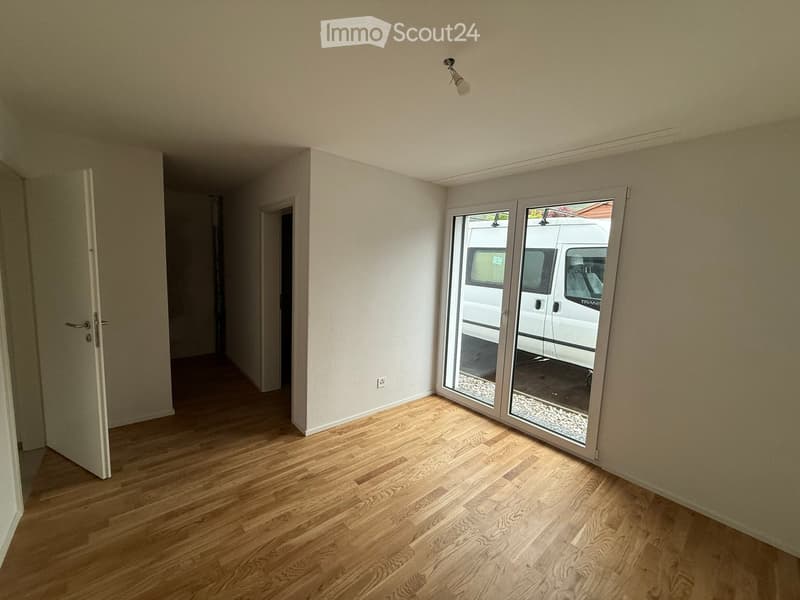 Unfurnished Room. Empty room with wooden flooring, white walls, and a sliding glass door leading to an outdoor area.