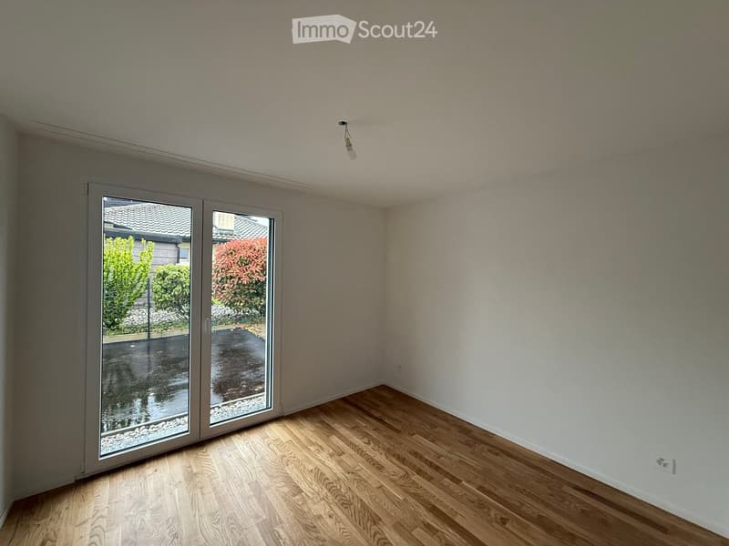 Unfurnished Room. Empty room with wooden flooring, large sliding glass door leading to an outdoor area, and visible light fixture on the ceiling.