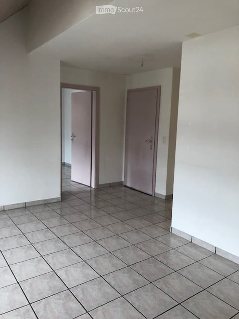Empty room with tiled floor and two doors, one leading to another room.