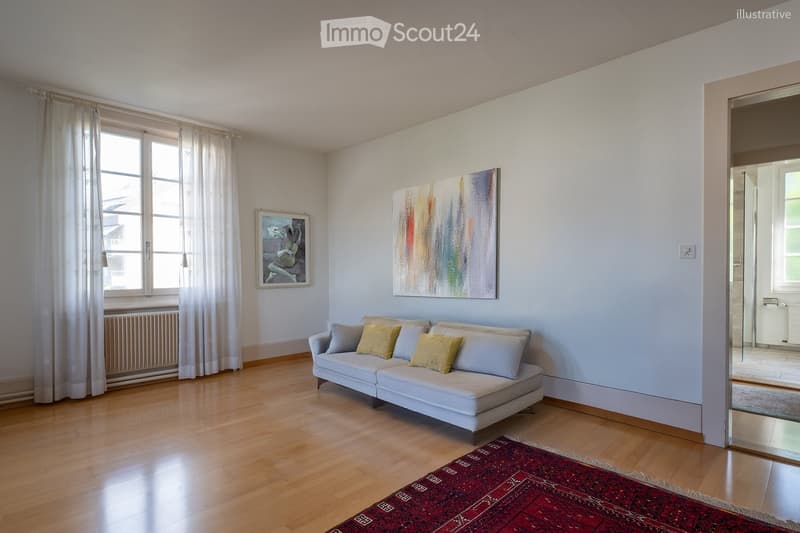 Bright living room with light blue walls, wooden floor, white sofa with multiple pillows, colorful abstract painting, large window with white curtains, radiator, and red patterned rug.
