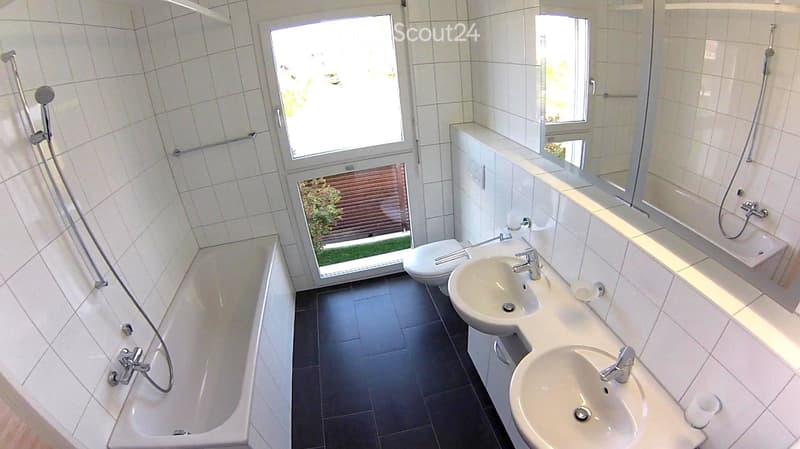 Bathroom. Modern bathroom with white tiles, black floor, bathtub, toilet, double sink, and mirror.