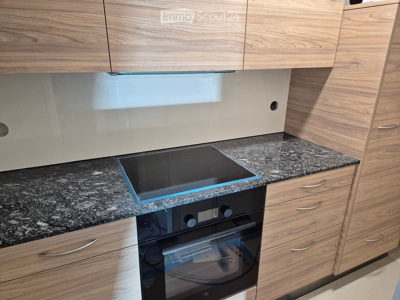 Modern kitchen with wooden cabinets, granite countertops, and built-in induction cooktop and oven.