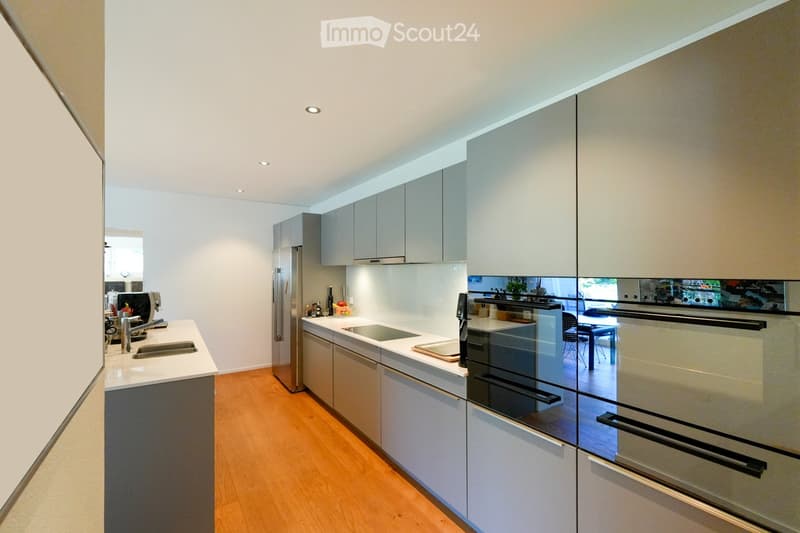 Modern kitchen with light grey cabinets, stainless steel appliances, and a central island with a sink and faucet.