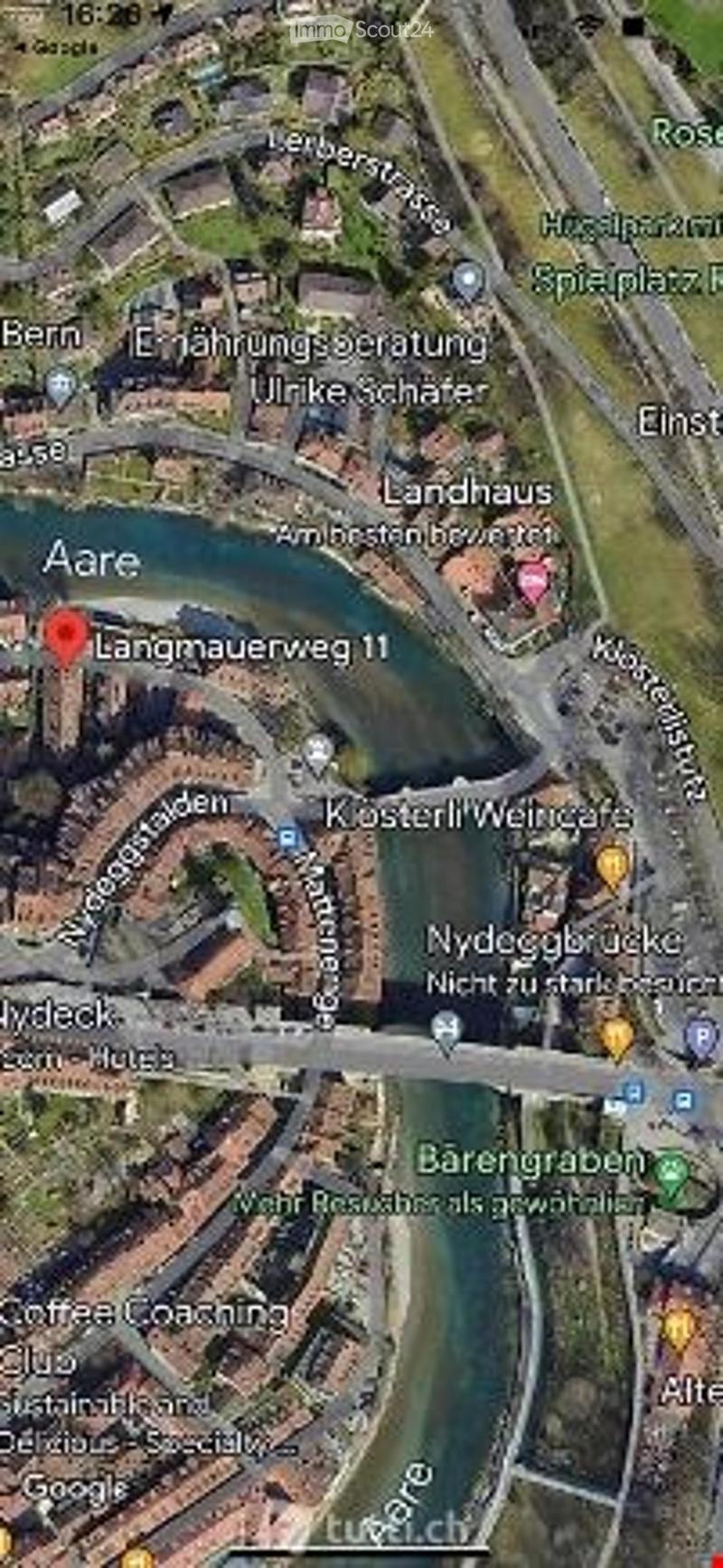 Aerial view of a city area showing streets, buildings, and a river. The location is marked as Langmauerweg 11, with surrounding landmarks including Landhaus and Kösterli Weinkafe.