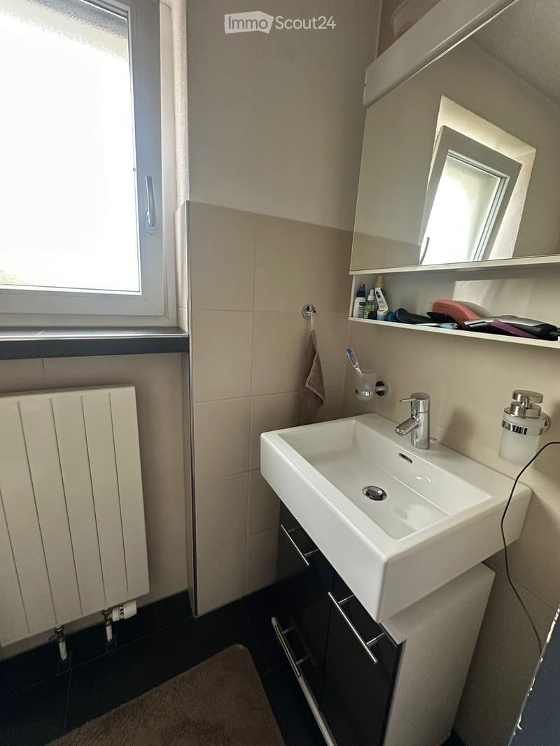 Modern bathroom with a white sink, chrome faucet, built-in mirror cabinet, and tiled walls.