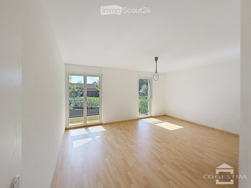 Empty room with wooden flooring, white walls, and large glass doors leading to a balcony area.