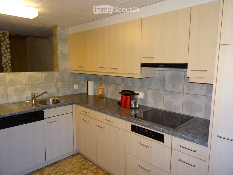 Modern kitchen with light wood cabinets, granite countertops, stainless steel sink, dishwasher, electric stove, and coffee maker.